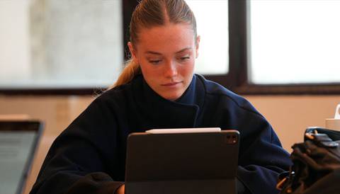 Una joven concentrada usando una tablet en un ambiente de trabajo.