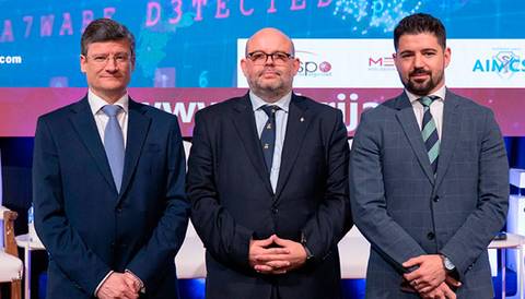 Tres hombres vestidos de traje posan para una foto en un evento oficial.