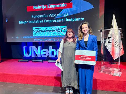 Un evento de entrega de un premio a la mejor iniciativa empresarial incipiente con dos mujeres posando en el escenario.