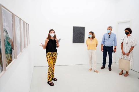 Una guía explica una exposición de arte contemporáneo mientras un grupo escucha atentamente.