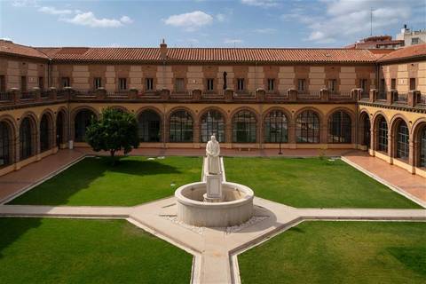 Vista de un patio interior con una estatua en el centro y edificios de fondo.