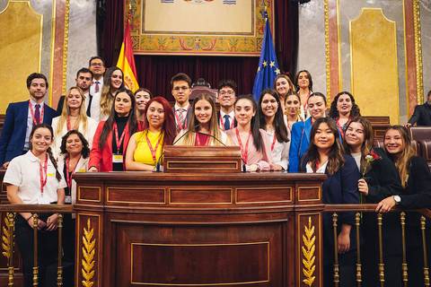 Grupo de jóvenes posando en un escenario político.