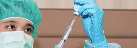 Un profesional de la salud prepara una inyección con una jeringa y un vial.