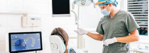 Un dentista está asistiendo a un paciente en una clínica dental mientras utiliza tecnología moderna para el diagnóstico.