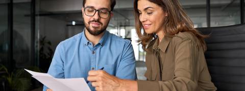 Una mujer y un hombre revisan documentos juntos en un entorno de oficina.