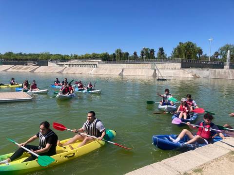 Un grupo de personas disfruta de una actividad de kayak en un estanque bajo un cielo despejado.
