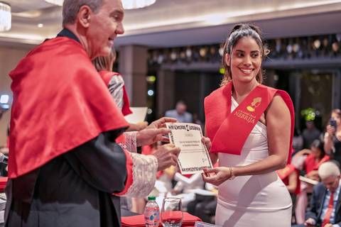 Una mujer sonriente recibe un diploma durante una ceremonia de graduación.