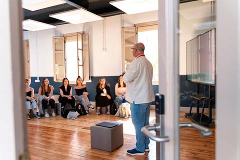 Un hombre está hablando frente a un grupo de mujeres en una sala de clase moderna.