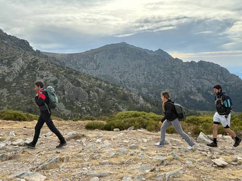 Tres personas caminan por un paisaje montañoso durante una excursión.