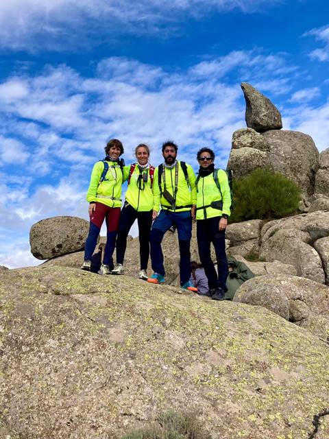Cuatro personas vestidas con chaquetas amarillas brillantes posan sobre rocas en un ambiente montañoso.