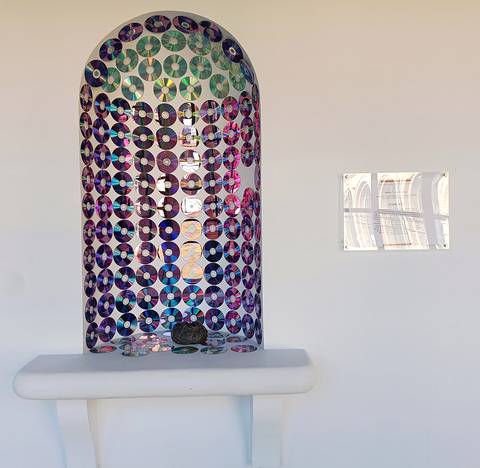 Una ventana decorada con discos compactos y una pequeña mesa blanca en la parte inferior.