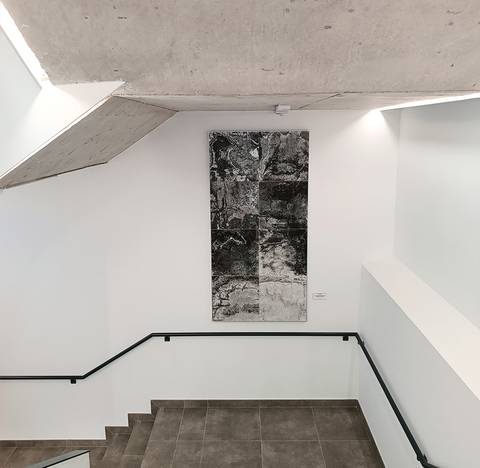 Una escalera interior con una obra de arte abstracto en la pared.