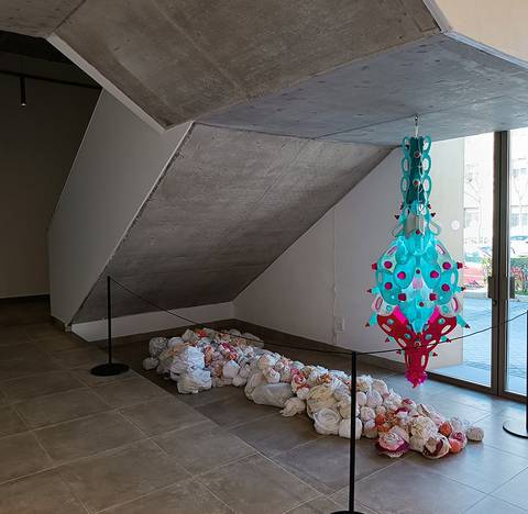 La imagen muestra un espacio interior con una estructura de concreto y una instalación artística colorida en el suelo.