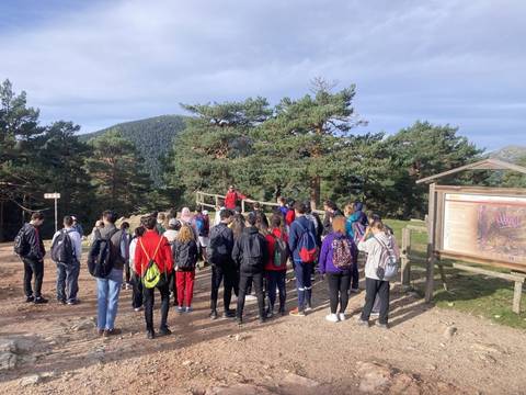 Un grupo de estudiantes escucha a un guía en un entorno natural montañoso.