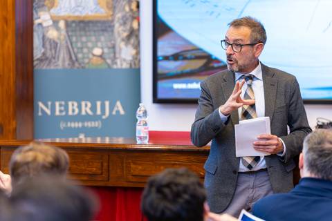 Un hombre presenta un tema frente a una audiencia en un evento académico.