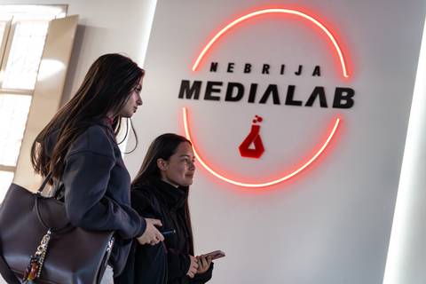 Dos mujeres conversan frente a un letrero iluminado que dice 'NEBRIJA MEDIALAB'.