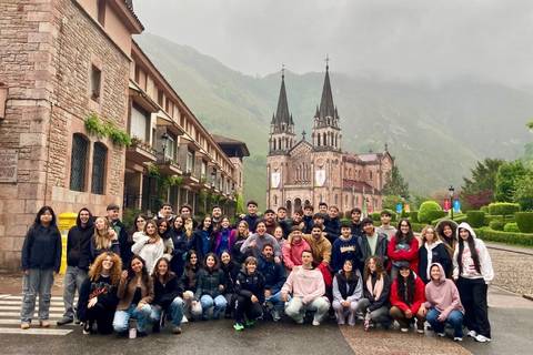 Un grupo de estudiantes posando frente a una iglesia gótica rodeada de montañas.