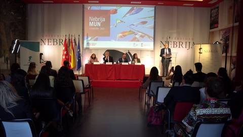 Un evento académico en la Universidad Nebrija con un panel de expertos y asistentes en un aula equipada.