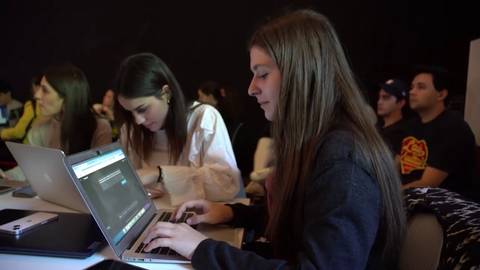 Un grupo de jóvenes está trabajando en sus computadoras portátiles en un ambiente de aprendizaje.