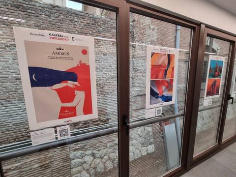 Una galería de arte muestra carteles en un espacio con paredes de ladrillo.