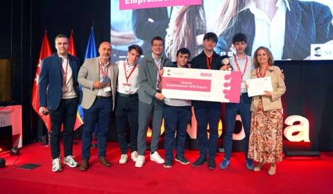 Un grupo de jóvenes emprendedores posando en un evento de premiación con trofeos y un certificado.
