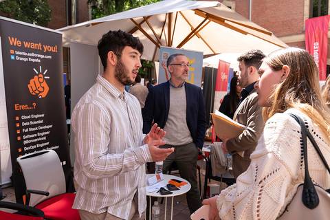 Una feria de empleo donde jóvenes interactúan con representantes de empresas.