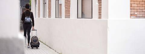 Una persona camina por un pasillo llevando una maleta con ruedas.