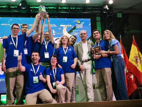 Un grupo de jóvenes vestidos con camisetas azules celebra con trofeos en un evento.