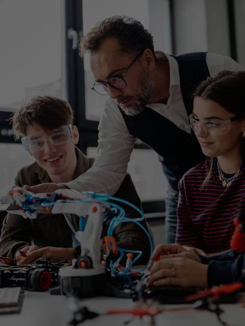 Un grupo de estudiantes trabaja en un proyecto de robótica bajo la supervisión de un profesor.