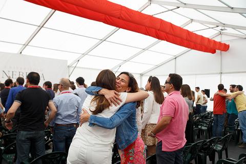 Un grupo de personas se abraza en un evento social bajo una carpa.