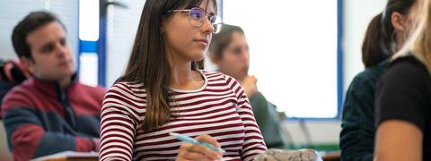 Una estudiante presta atención en clase mientras toma notas.