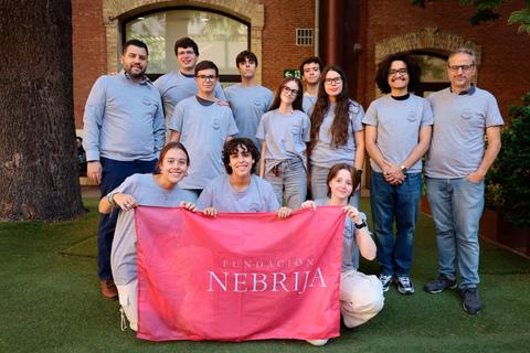 Grupo de personas posando juntos con una bandera de la Fundación Nebrija.