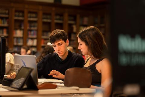 Dos jóvenes estudian juntos en una biblioteca.