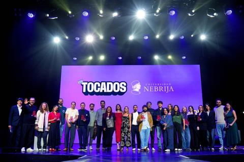 Un grupo de personas posando en un escenario con un fondo que presenta un evento relacionado con la Universidad de Nebrija.