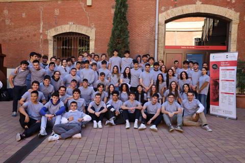 Un grupo grande de estudiantes posando al aire libre frente a un edificio.