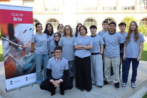 Un grupo de jóvenes sonrientes se reúne frente a un cartel del 'Club de Arte'.