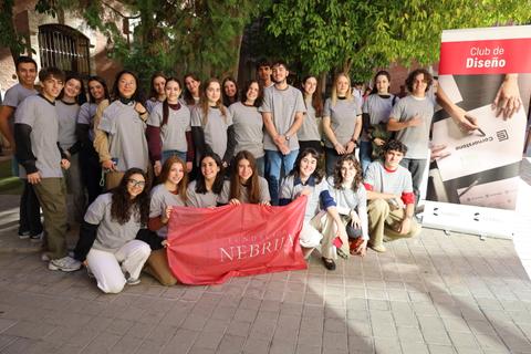 Un grupo grande de personas posando juntas con camisetas grises y una bandera del Club Nebrija.