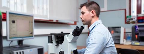 Un científico observa a través de un microscopio en un laboratorio.