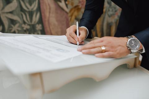 Una persona está firmando un documento sobre una mesa blanca.