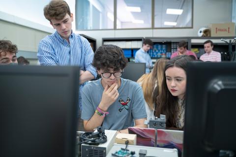 Un grupo de estudiantes trabaja en un proyecto en un aula, concentrados en sus computadoras.