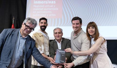 Un grupo de cinco personas sostiene un libro durante un evento sobre realidad virtual y aumentada.
