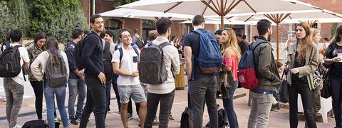 Un grupo de personas conversando al aire libre en un ambiente universitario.