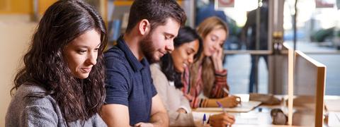 Un grupo de jóvenes estudia en una mesa en un espacio abierto.
