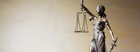 La imagen muestra una estatua de la diosa Justicia sosteniendo una balanza y una espada.