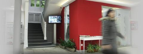 Una entrada moderna con una pared roja y una persona caminando frente a un monitor.